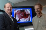 MIT research scientist Rutledge Ellis-Behnke, left, and Professor Gerald Schneider stand by a monitor showing a transected liver that has been sealed with a substance that can stop bleeding within seconds of application.
