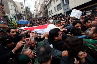 Mourners carry the Iranian flag-covered body of a murdered physicist