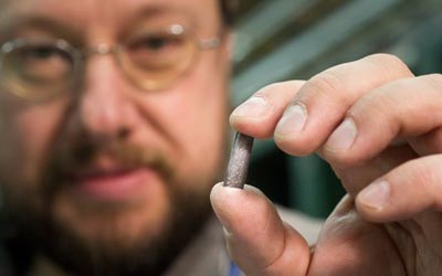 Detlef Kuchler, a physicist in CERN's beams department, holds a piece of the lead source material used to create heavy ions for the LHC. (Courtesy: M Brice/CERN)
