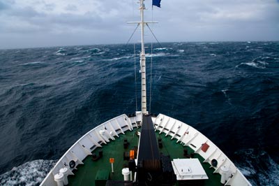 Photograph of a ship facing large waves