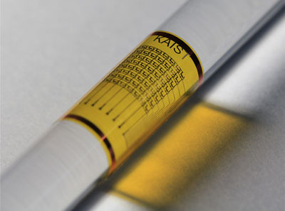 A photograph of a flexible memory device bent round a plastic rod