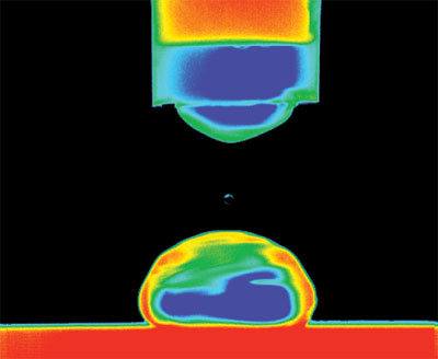 Colour-enhanced image of water droplet being deposited on a silicon surface