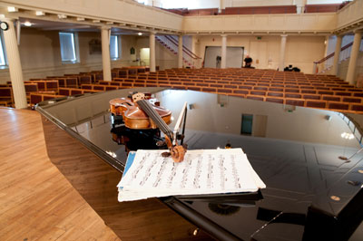 A photograph of a violin resting on a piano